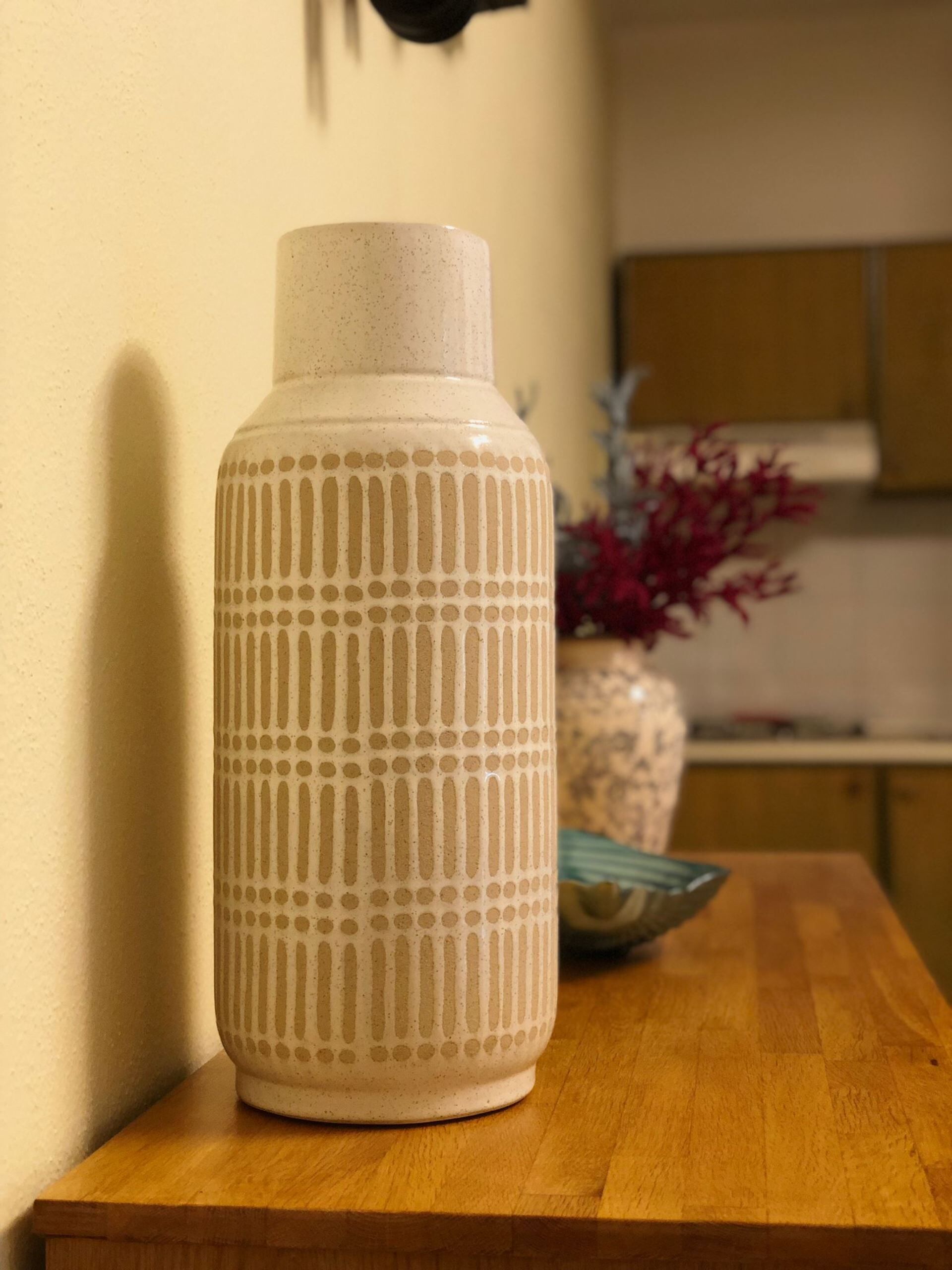 Un jarrón de cerámica con un diseño acanalado sobre una mesa de madera.