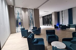 A spacious lobby with modern furniture and a large window. - Kastin Hotel (Shantou)