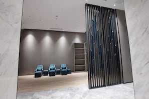A room with a wooden floor, a set of blue chairs, a ladder, and a metal partition. - Kastin Hotel (Shantou)