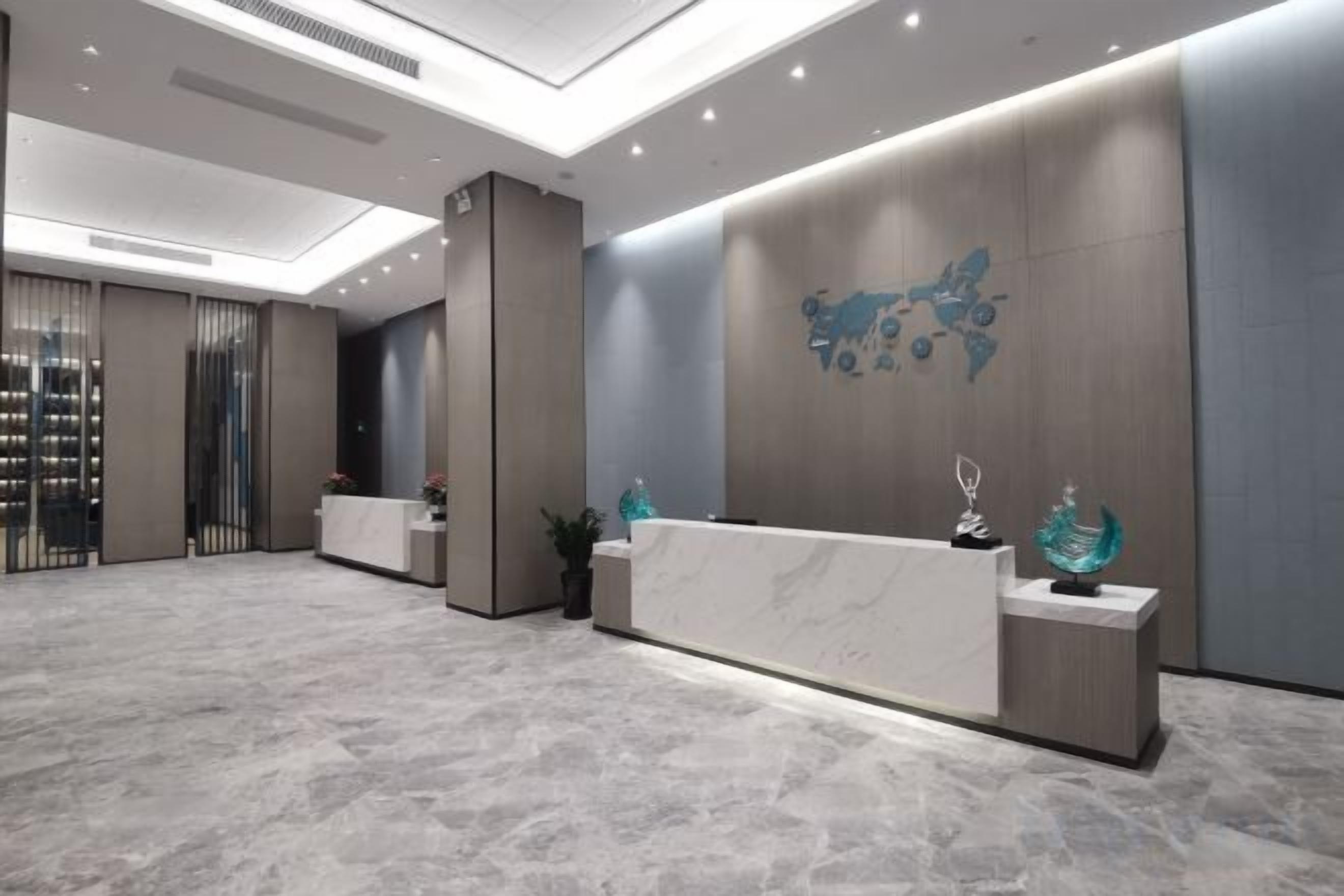 A reception area with a marble floor, a reception desk, and a wall-mounted decorative piece.