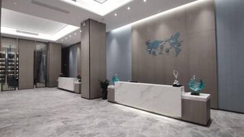 A reception area with a marble floor, a reception desk, and a wall-mounted decorative piece.