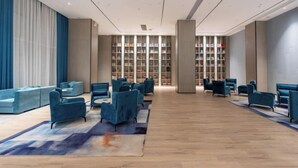 Un hall amplio con una zona de estar central, una gran estantería y un diseño moderno.