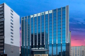 Um edifício de hotel moderno com fachada de vidro e uma placa com o nome