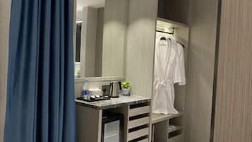 A modern bathroom with a vanity, a mirror, a robe hanging on a rack, and a shower area.