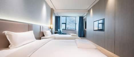 A hotel room with two beds, a large window, a view of the city, and a modern design.