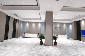 A spacious lobby with a reception desk, two potted plants, and a modern ceiling design. - Kastin Hotel (Shantou)