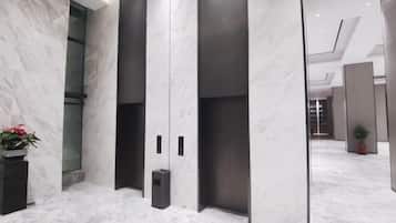 A modern elevator area with marble walls and a potted plant.