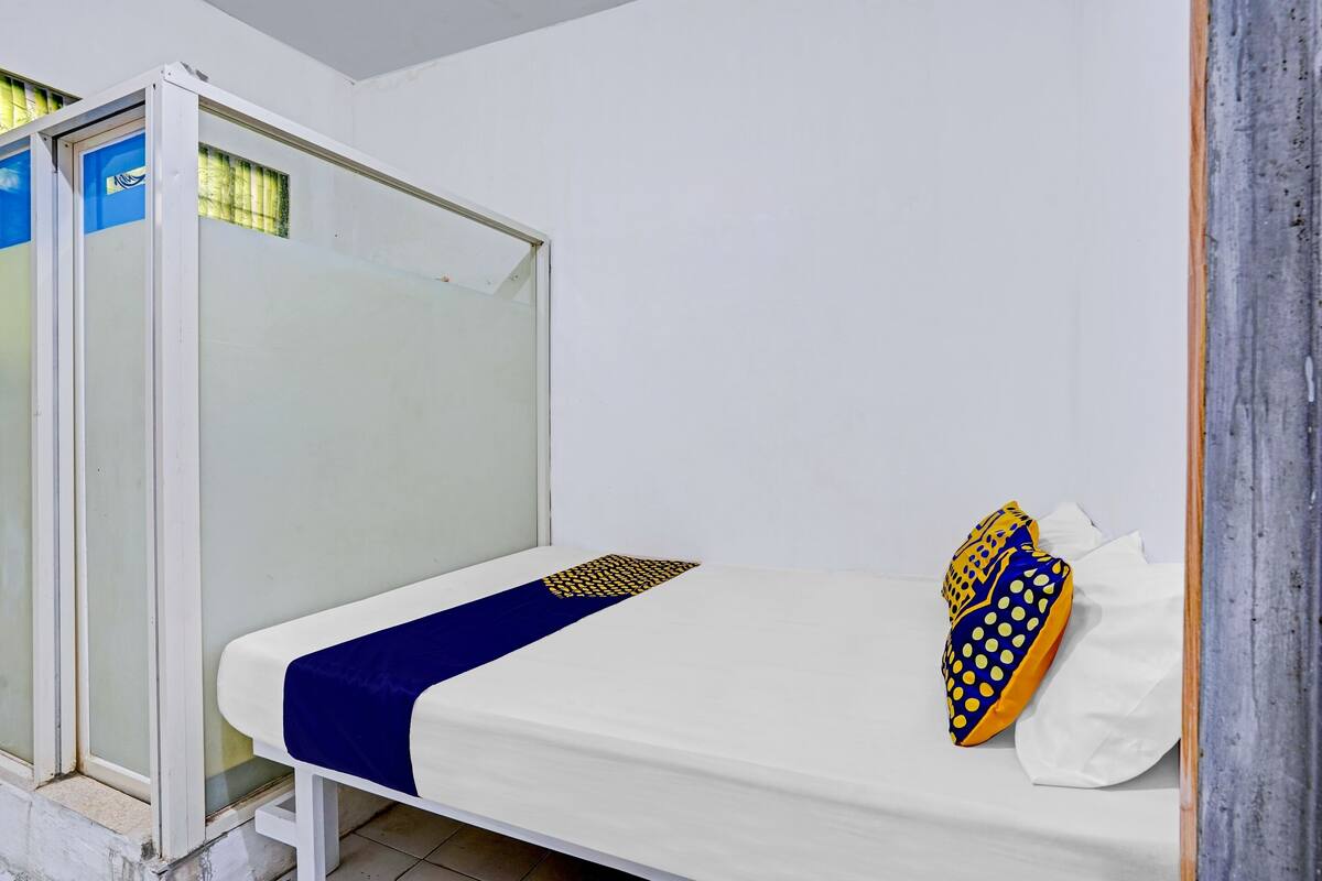 Ein Einzelbett mit weißer Matratze, einer blauen Decke und zwei Kissen mit Punkten.