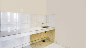 A small, clean bathroom with white tiles, a sink, and a toilet. - Hotel O Pondok Dukuh (Nusa Dua)
