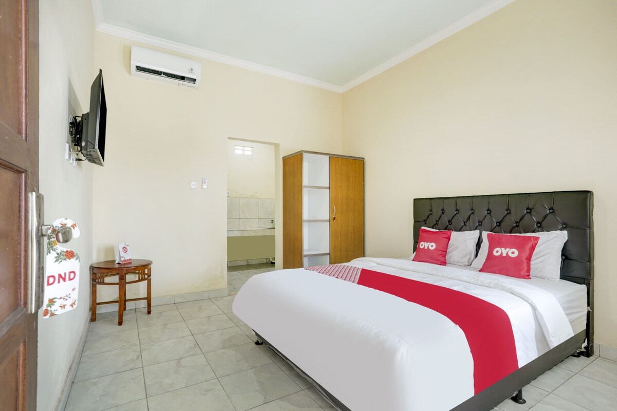 Habitación de hotel con cama, una mesita, armario y equipo de aire acondicionado.