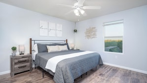 A bedroom with a bed, nightstand, wall art, and a window. - 3BR Ozark View Condo | Sleeps 11 (Branson)