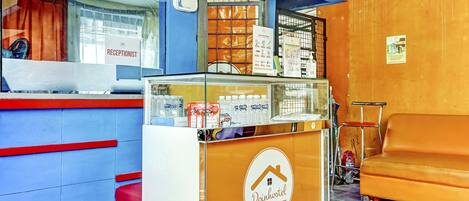 Una zona de recepción con mostrador, un letrero de recepcionista y un sofá.