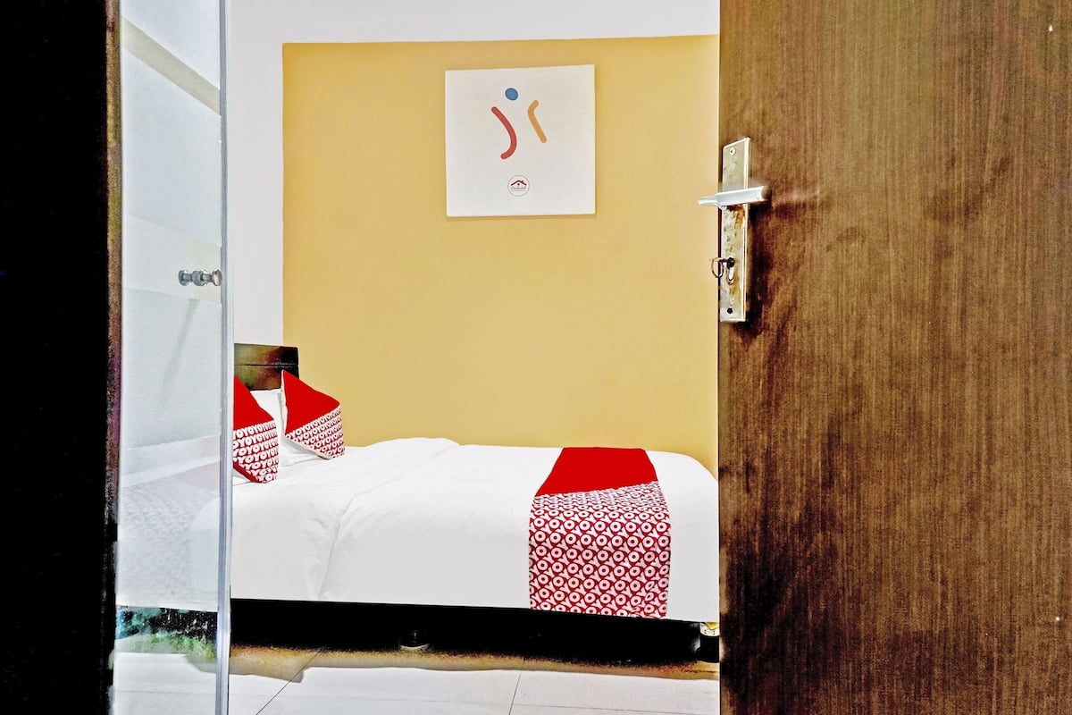 Quarto de hotel com cama, porta e parede com uma moldura.
