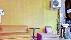 A corner with a brown leather sofa, a small round table, and a purple ottoman.