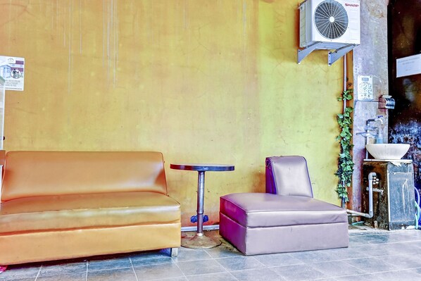 A corner with a brown leather sofa, a small round table, and a purple ottoman.