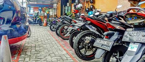Una hilera de motocicletas estacionadas en una calle adoquinada frente a un edificio con un letrero que dice 'Curry Garden'.