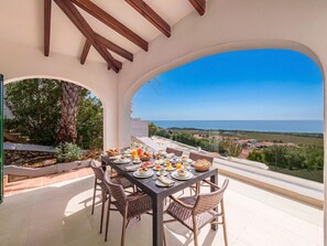 A dining area with a table set for breakfast, overlooking a scenic landscape. - Villa Atalis, Stunning sea views (San Jaime Mediterráneo)