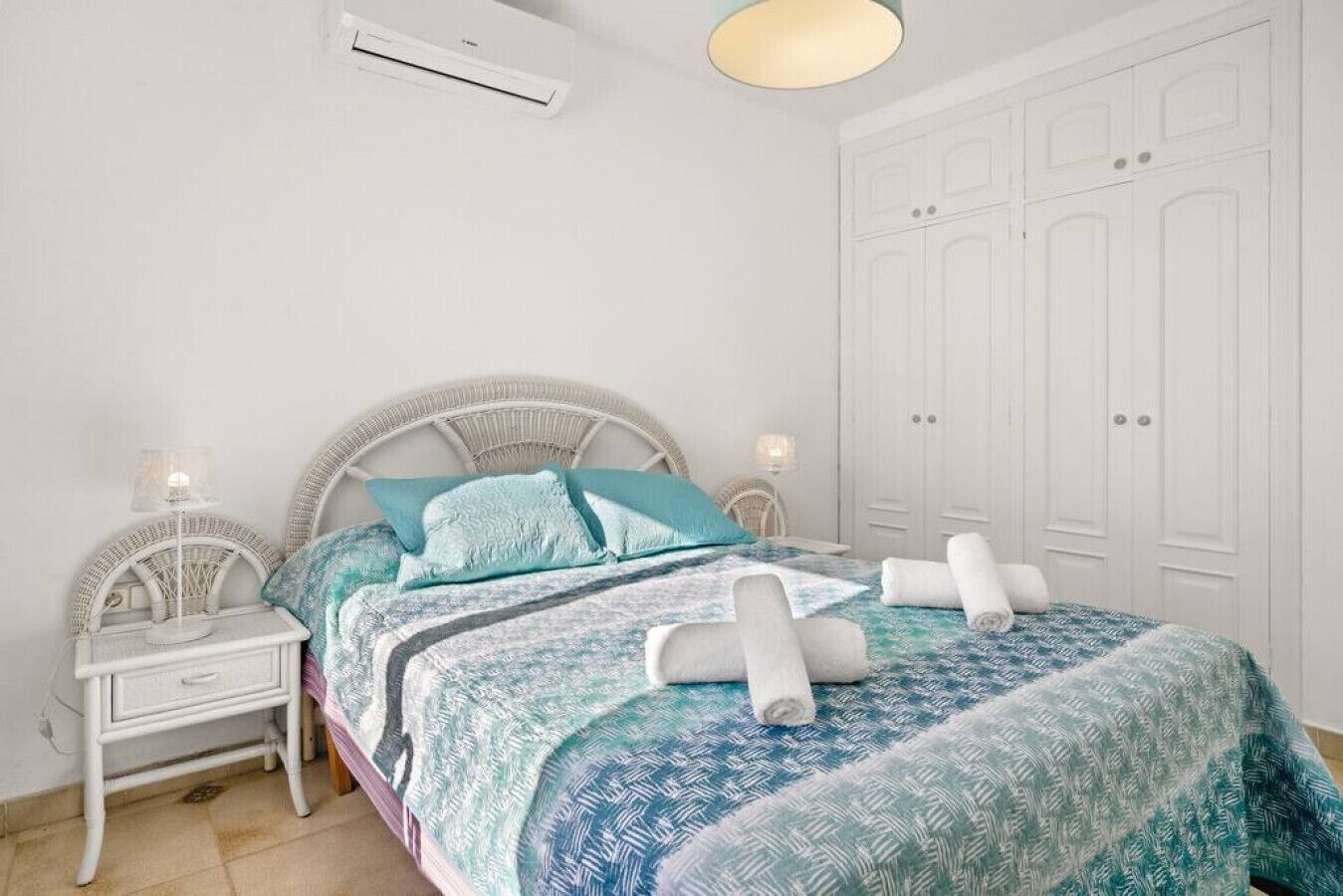 A bedroom with a bed, nightstands, an air conditioning unit, and a wardrobe.