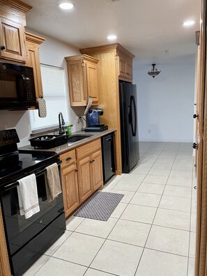 A kitchen with wooden cabinets, a black stove, a black refrigerator, and a coffee maker.