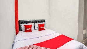 Ein Bett mit schwarzem Kopfteil, weißer Bettwäsche und roten Akzenten.