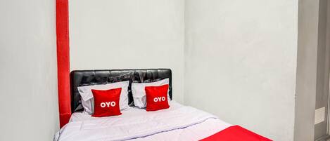 A bed with a black headboard, white bedding, and red accents.