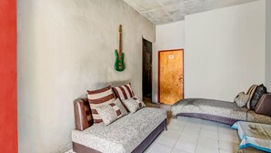 Ein Zimmer mit einer Couch, einer grünen Gitarre und einer Holztür.