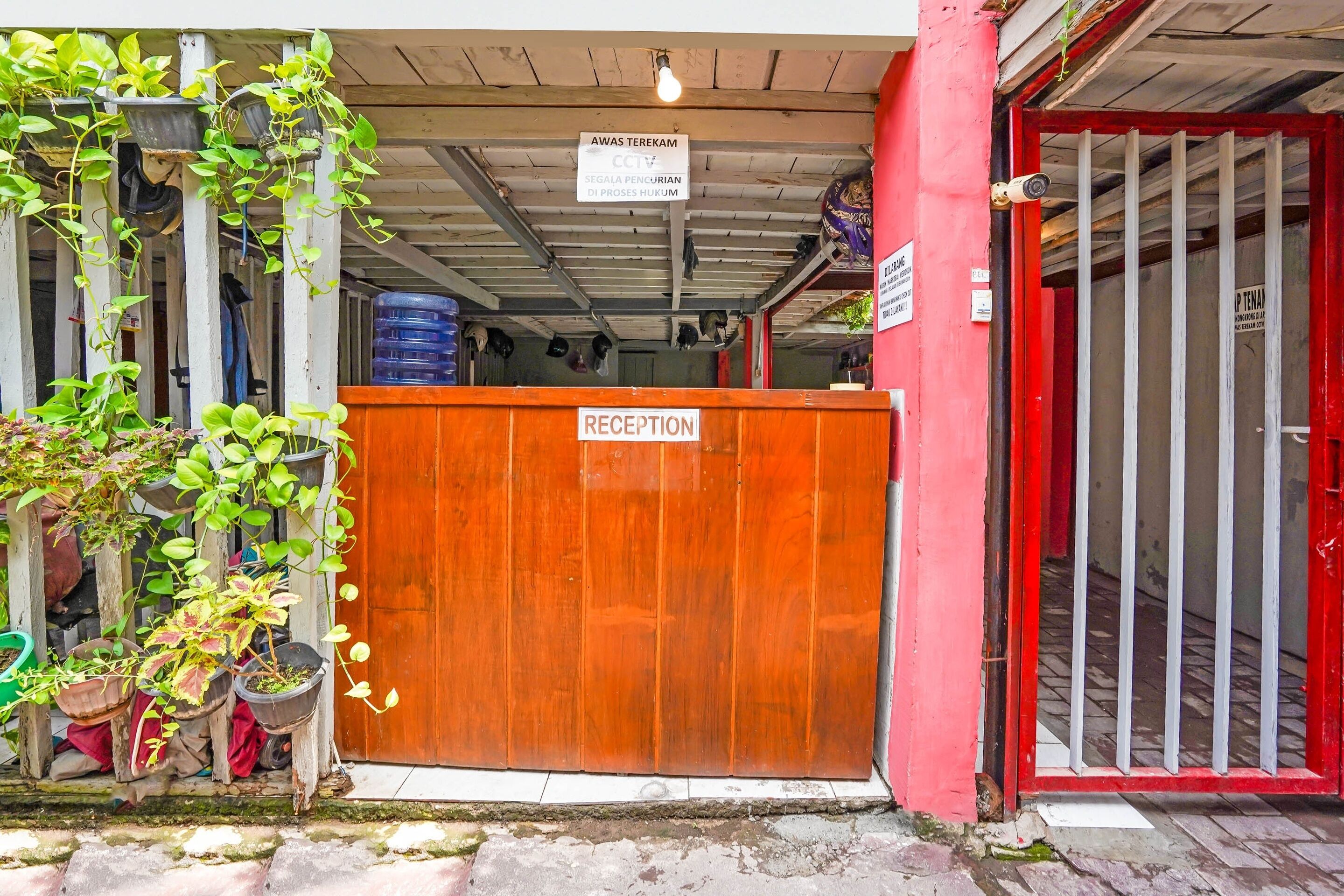 A reception area with a wooden gate, potted plants, and a sign indicating a waiting area.