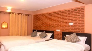 Ein Hotelzimmer mit zwei Betten, jedes mit gemusterten Kissen, einer Ziegelwand und einer kleinen, beleuchteten Wanddekoration.