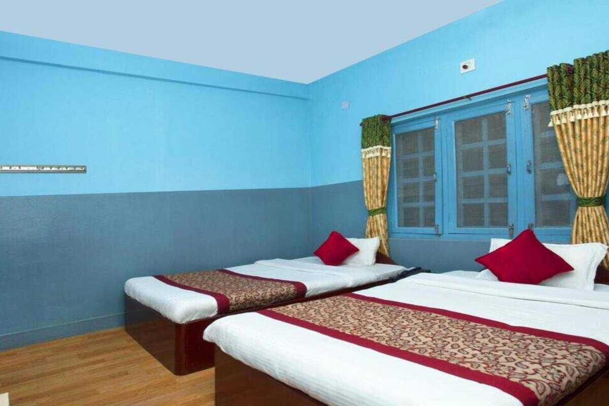 Une chambre avec deux lits, des murs bleus et une fenêtre avec des rideaux.