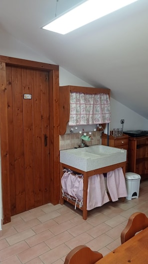 Cozinha pequena com porta de madeira, pia e bancada.