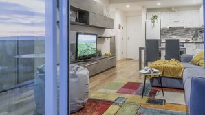 Uma sala de estar moderna com uma televisão, um sofá, uma mesa de centro e um tapete colorido.