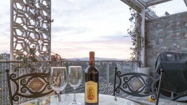 Uma mesa com uma garrafa de vinho e duas taças, com uma vista panorâmica ao fundo.