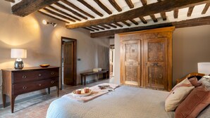 Une chambre à coucher avec un lit, une armoire en bois, une commode et une lampe.