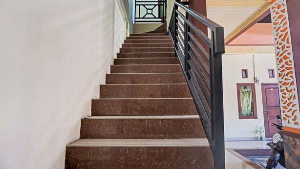 Un escalier muni d’une rampe, menant à un palier avec une porte et un mur orné d’un panneau décoratif.