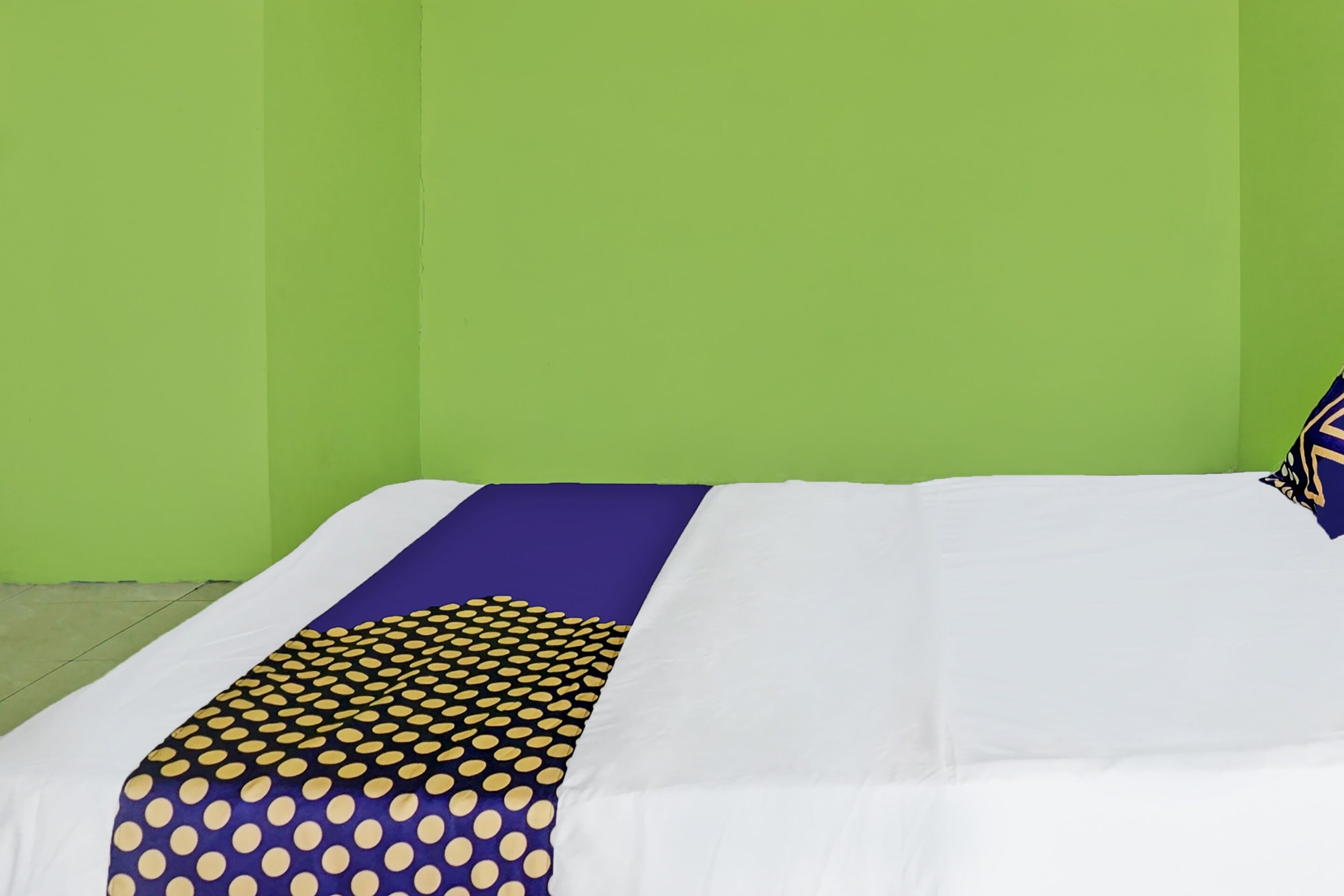 A bed with a white mattress and a blue and yellow polka dot blanket.