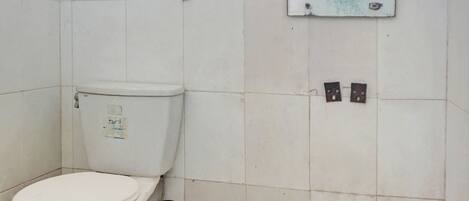 A small, tiled bathroom with a toilet, a wall-mounted sink, and a window above the sink.