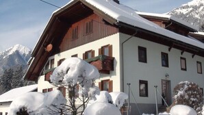 Un chalet traditionnel doté d’un toit à pente, de volets en bois et de fondations en pierre.