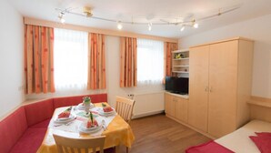 Une pièce de taille modeste comprenant une table à manger, des chaises, un canapé, un téléviseur et une armoire.