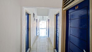 A corridor with blue doors, white walls, and a tiled floor. - Hotel O Darussalam Inn (Medan)
