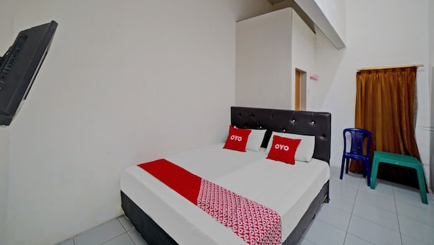 A neatly arranged bedroom with a bed, a chair, and a small stool. - Hotel O Darussalam Inn (Medan)