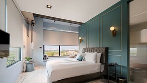 Un dormitorio moderno con una cama grande, vistas a la ciudad y una mesita con una planta.