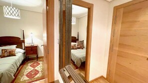 Une chambre à coucher avec un lit, une table de chevet, une lampe et un miroir.