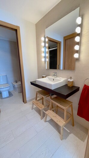 Une salle de bain moderne avec un grand miroir, un meuble-lavabo et des marches en bois.
