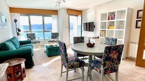 Ein Wohnzimmer mit einer Couch, Sesseln, einem Esstisch und einem Bücherregal.