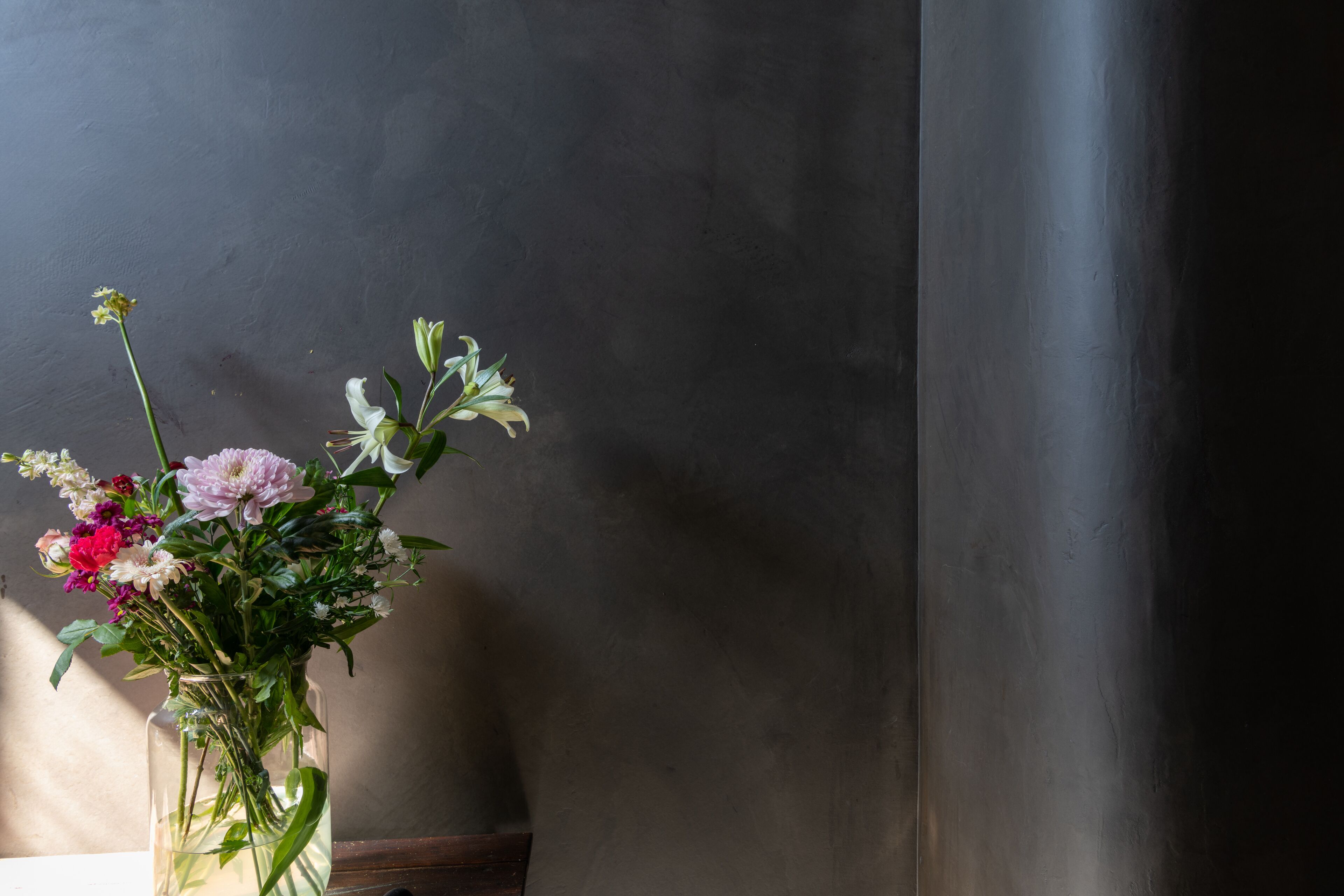 Une vue nette d’un vase rempli de fleurs, placé devant un mur uni.