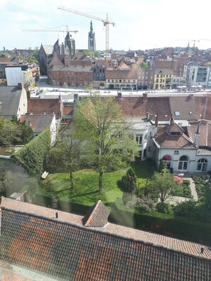 A residential area with traditional architecture, including a church with a clock tower, and a construction crane in the background. - BROEL4 (Kortrijk)