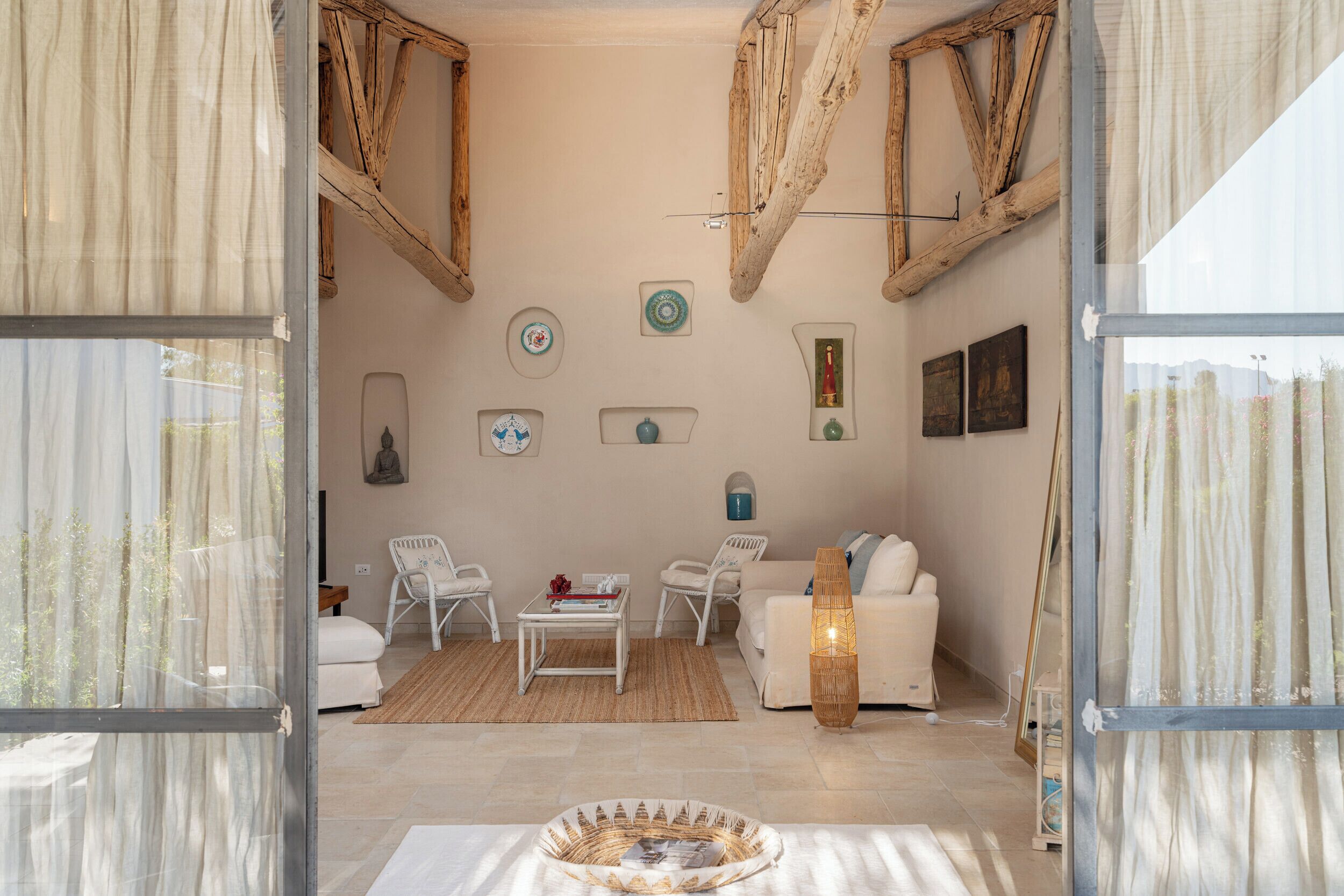 Un salon spacieux avec un canapé blanc, deux fauteuils blancs, une table basse et une lampe décorative.