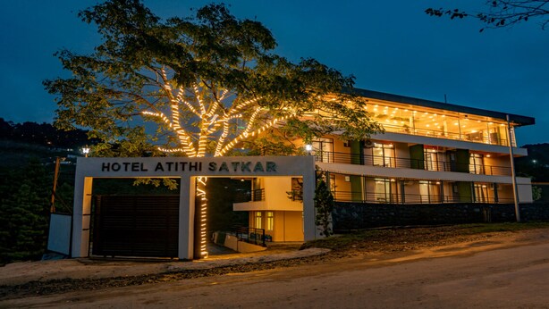 A hotel with a sign reading "HOTEL ATITHI SATKAR" and a tree with lights in front. - MeroStay 025 Atithi Satkar (Mahamanjushree Nagarkot)