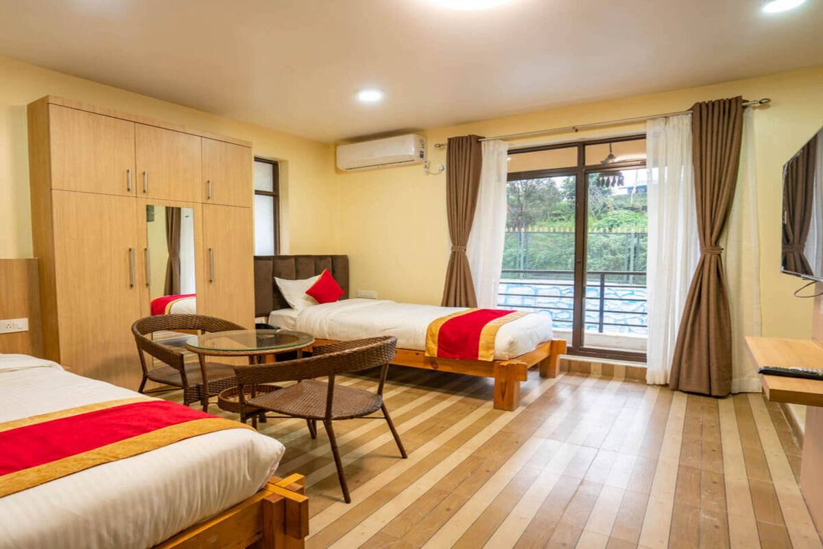 A hotel room with two beds, a dining table, and a TV.