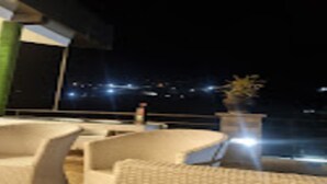 A rooftop terrace with outdoor seating and a view of the city at night. - MeroStay 025 Atithi Satkar (Mahamanjushree Nagarkot)